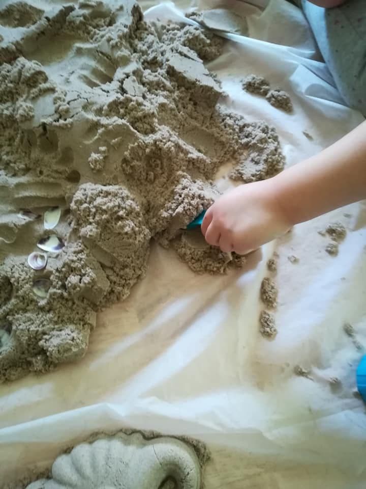 Terapia ręki - zbliżenie na rękę dziecka bawiącego się piaskiem kinetycznym