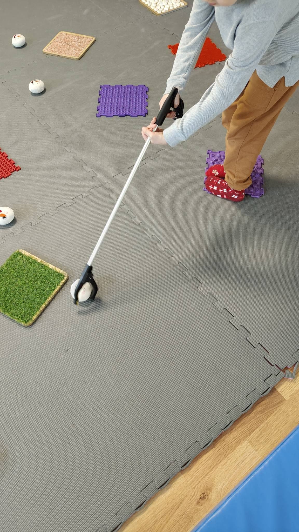 Terapia ręki - zbliżenie na rekę dziecka trzymającą chwytak za pomocą którego łapie piłkę