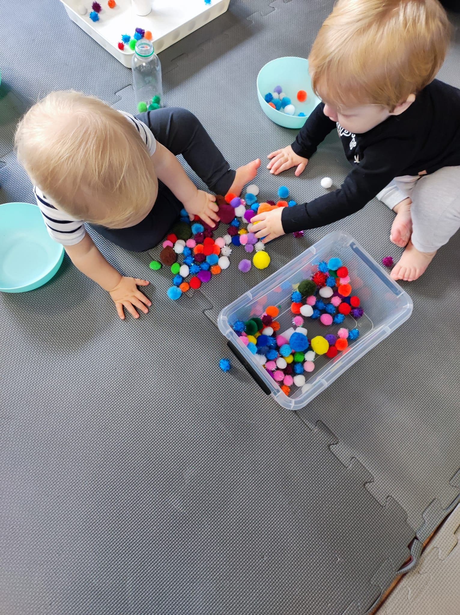 Smyko-multisensoryka - zbliżenie na rączki małych dzieci które bawią się pomponami