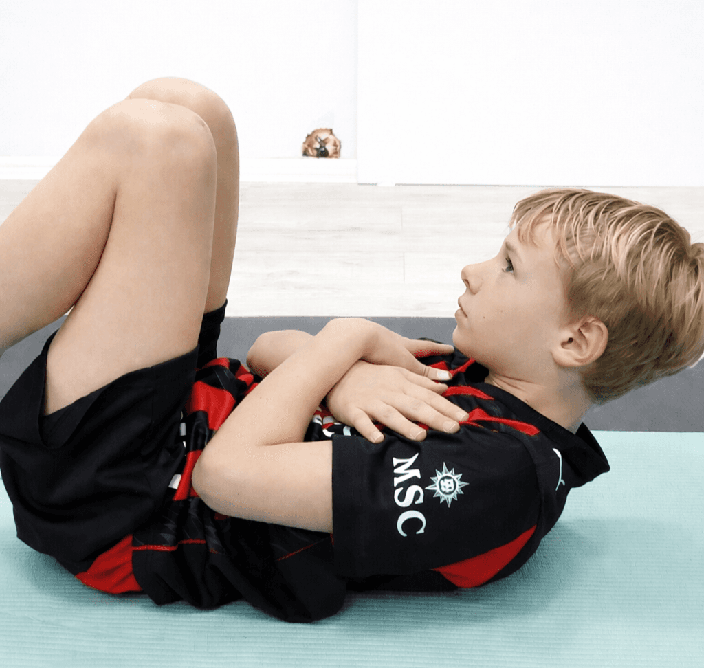 Chłopiec wykonuje pozycję zgięciową na plecach